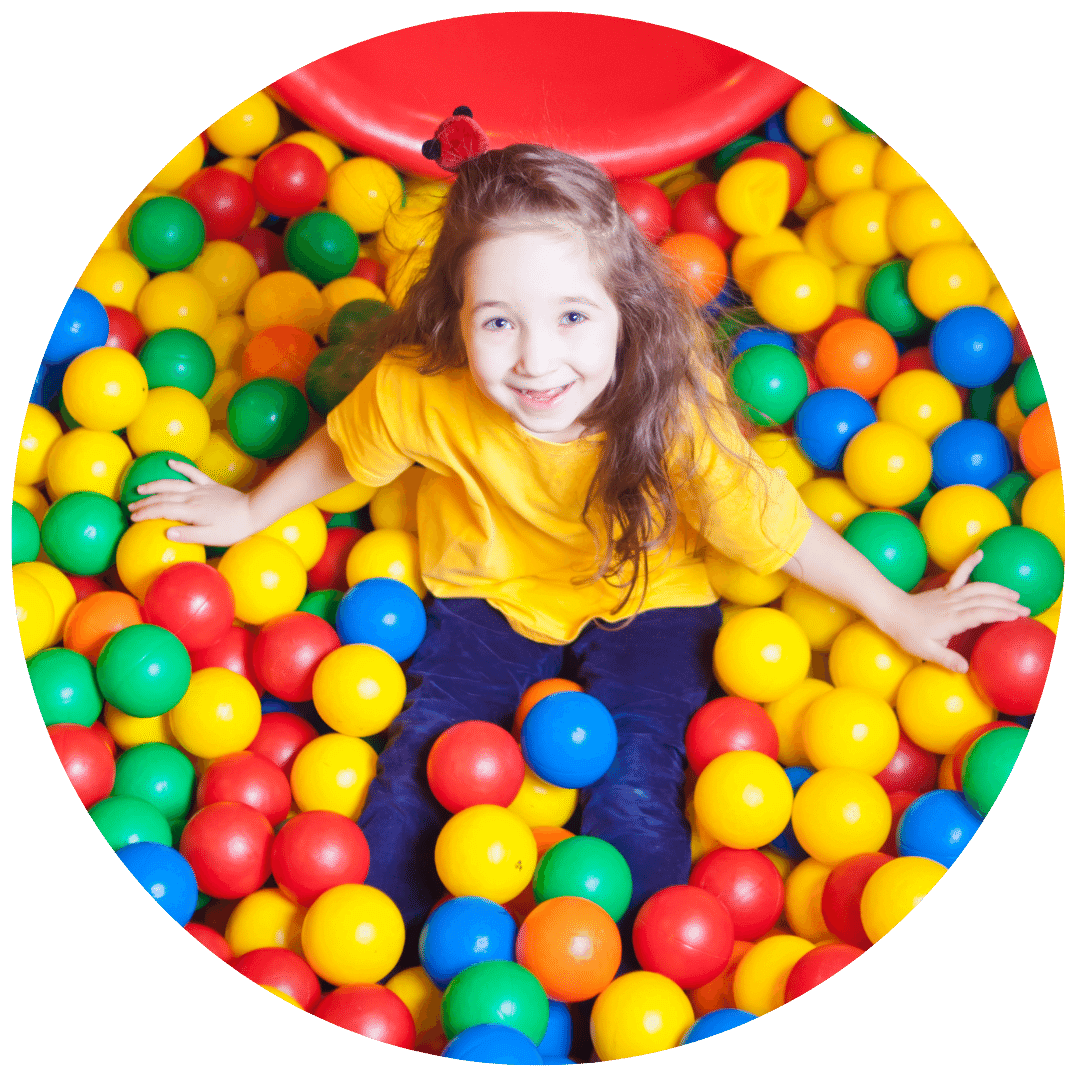 Young girl smiling while looking up towards in the camera inside of a ball pit.